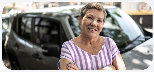 Mujer sonriendo posando en su automóvil