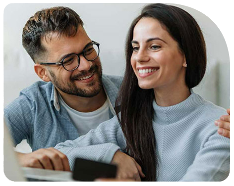 Pareja sonriendo frente a un computador inviertiendo en Fondos Mutuos