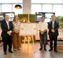 cuatro personas junto a una placa conmemorativa