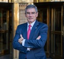 Hombre con traje y corbata roja participa en entrevista televisiva sobre medidas para reducir el dividendo y el pie de viviendas