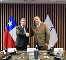Autoridades posan y se estrechan la mano frente a banderas chilenas durante una reunión de la Mesa Nacional de Fraude Financiero