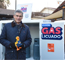 Persona con peluche Caja Vecina frente a gabinete de cilindros promocionando Cupón de Gas Licuado
