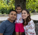 Familia sonríe junto a una niña en un parque