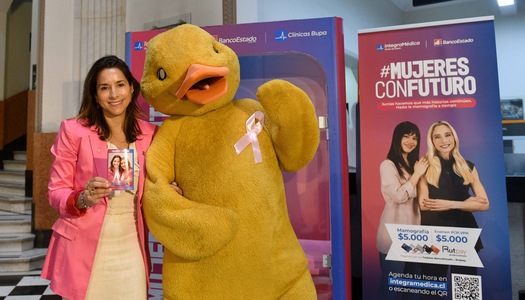 Mujer junto al Pato de BancoEstado en campaña de prevención del cáncer de mama.