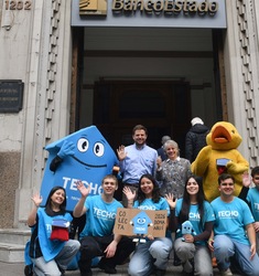 Voluntarios de TECHO junto a personajes de BancoEstado frente a una sucursal