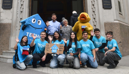 Voluntarios de TECHO junto a personajes de BancoEstado frente a una sucursal
